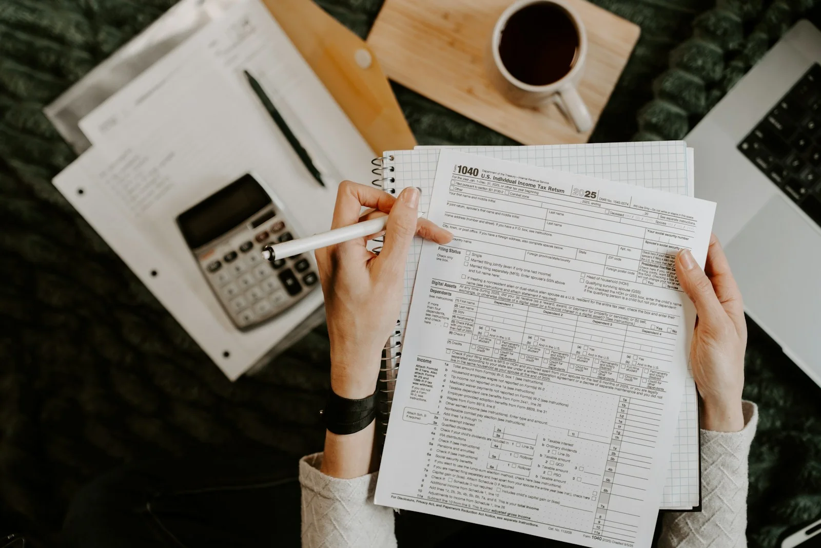 Reviewing a tax return with a notebook, calculator, and laptop.